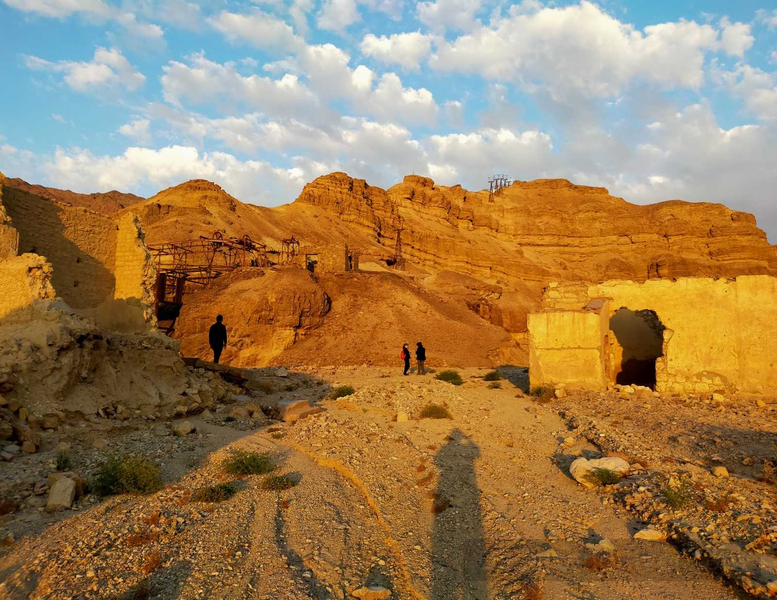 Ruins of the Um Bogma mining settlement in South Sinai at golden hour, with layered desert hills and scattered structures under a cloudy sky.