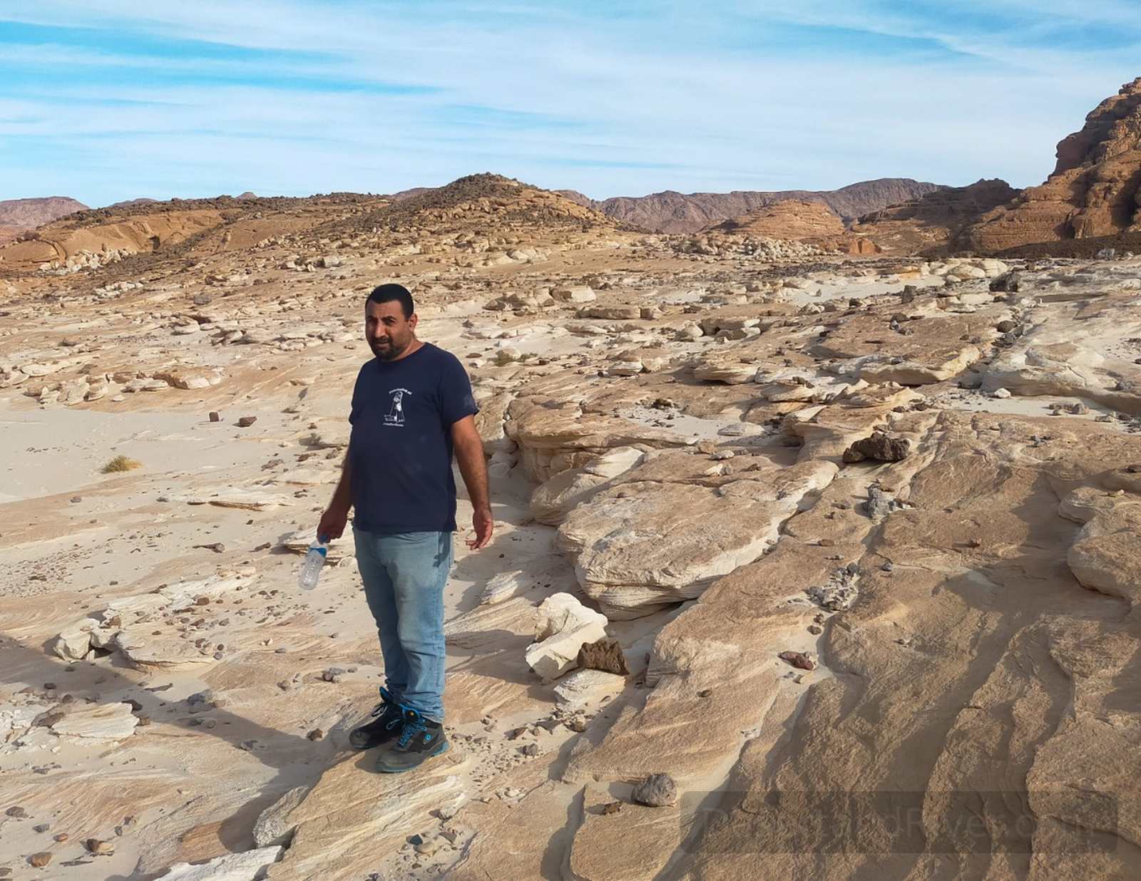 Magazah Valley and canyon route in South Sinai, with pale rock formations and a guide walking across the desert landscape under a blue sky.