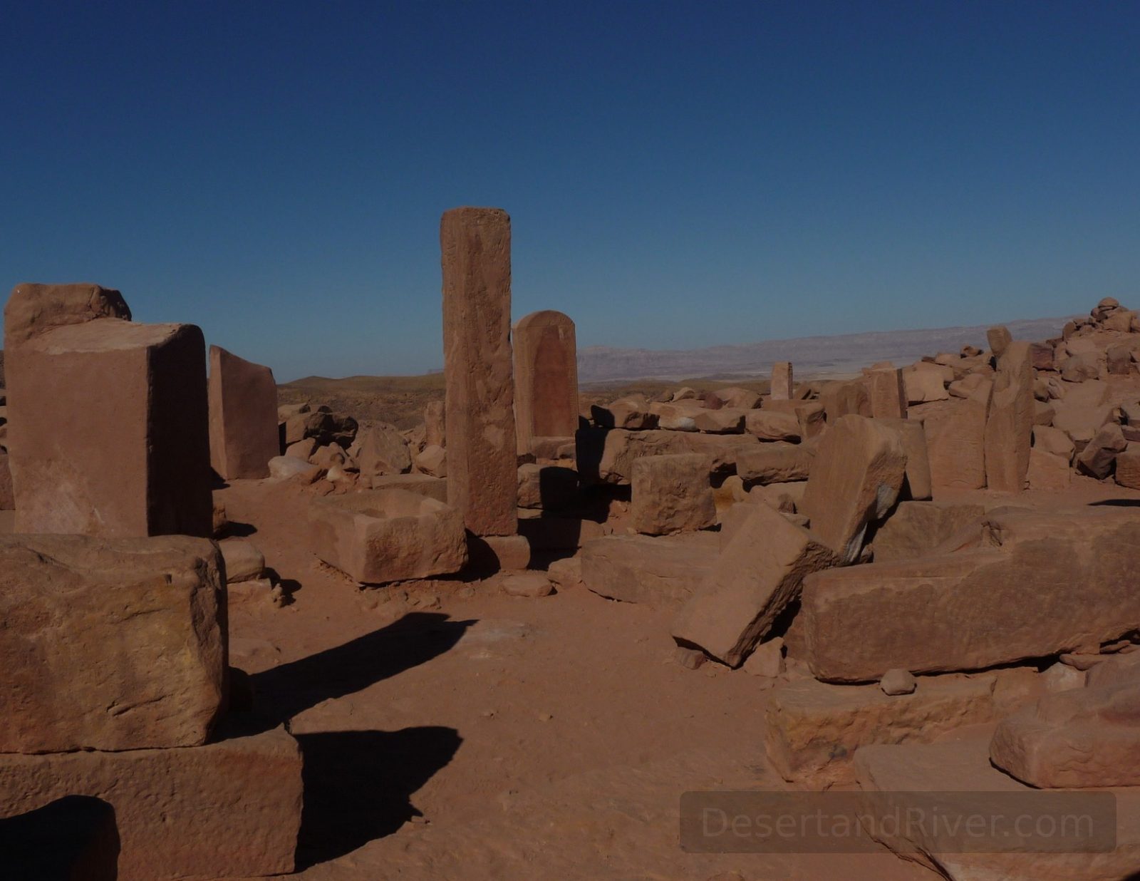 Serabeit el Kadim in southwestern Sinai, with scattered stone stelae and temple ruins on a desert plateau under a deep blue sky.