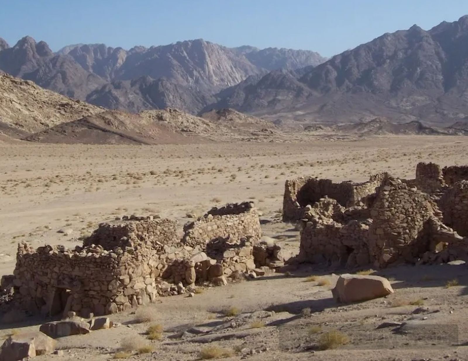 Ruins of a Nabataean stone settlement in South Sinai near Saint Catherine, with a wide desert plain and mountains in the background.