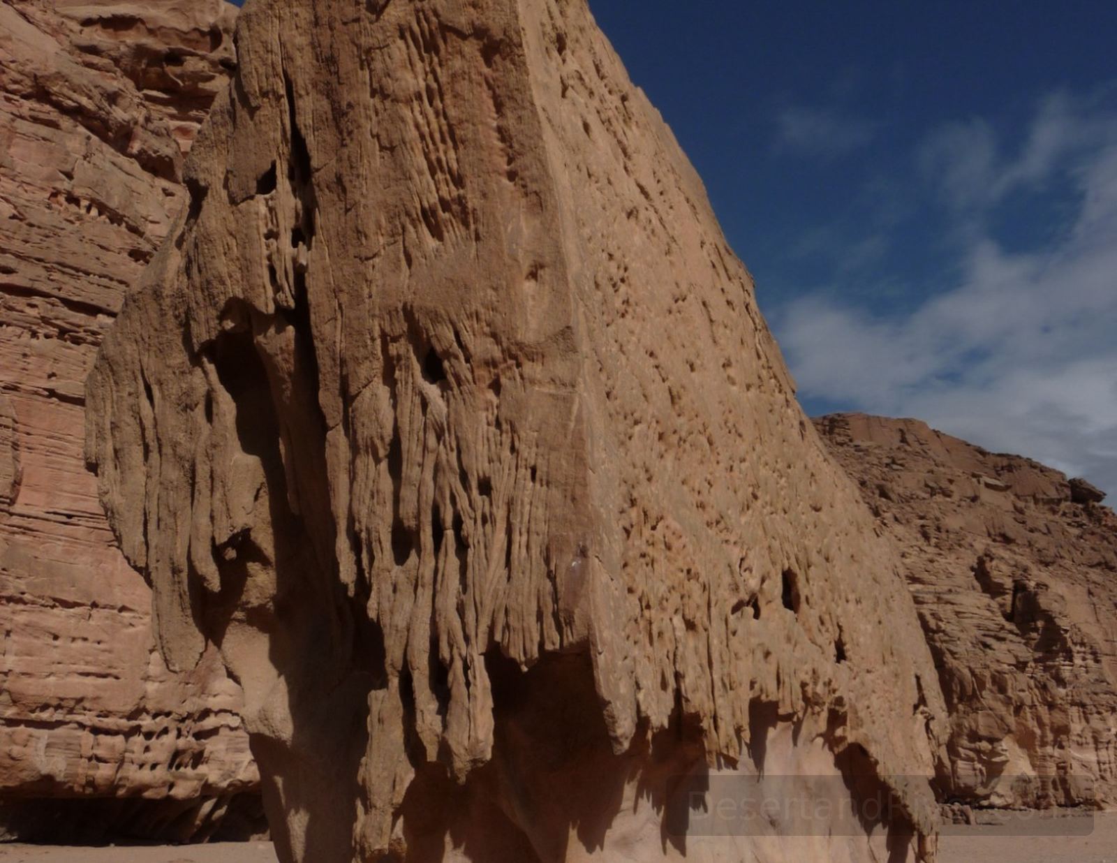 Tall sandstone wall in Wadi el Disco, southern Sinai, rising above an open desert valley under a deep blue sky.